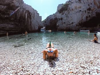 Woman relaxing at beach against mountains