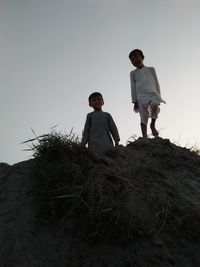 Low angle view of men standing against clear sky