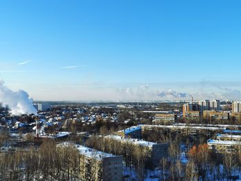 High angle view of buildings and trees against blue sky