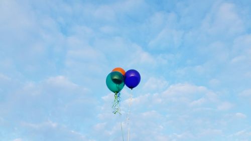 Low angle view of balloons flying against blue sky