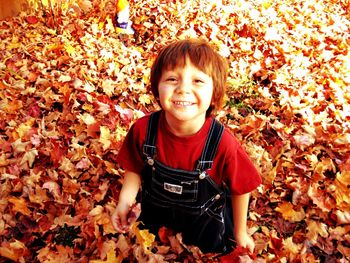 Portrait of boy surrounded by autumn leaves