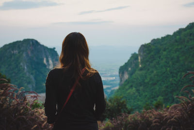 Rear view of woman standing on mountain against sky