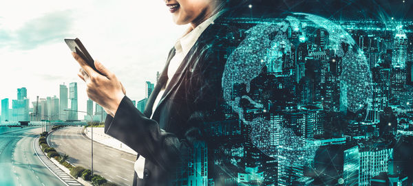 Low angle view of woman using mobile phone against buildings in city