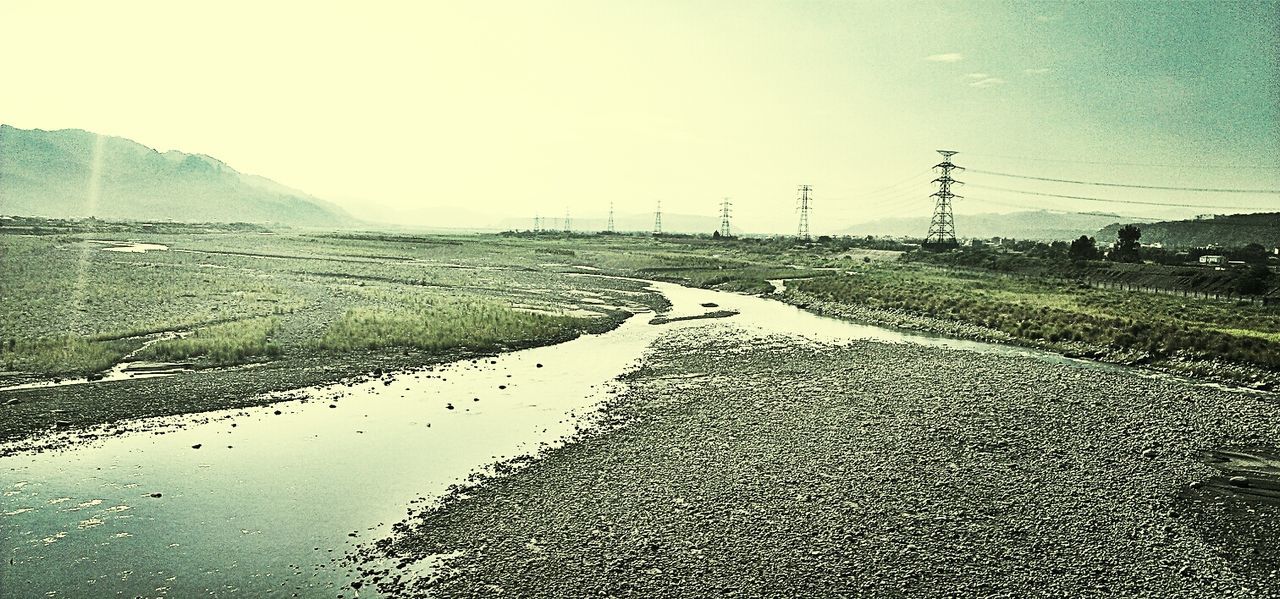 water, road, electricity pylon, transportation, tranquility, tranquil scene, landscape, sky, the way forward, clear sky, nature, diminishing perspective, scenics, power line, beauty in nature, field, wet, vanishing point, day, outdoors