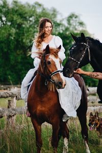 Woman sitting on horse against tree