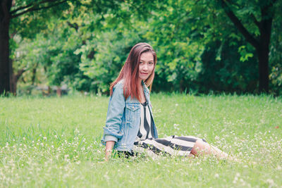 Portrait of young woman using mobile phone in field