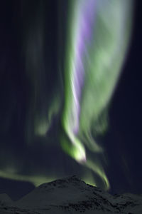 Aurora borealis over snowcapped mountain at night