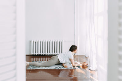 Side view of man sitting on wooden floor