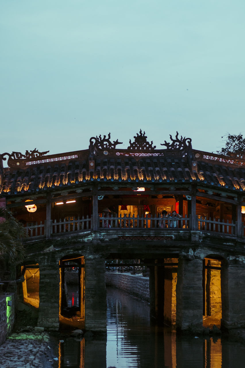 BUILDING BY LAKE AGAINST SKY AT DUSK