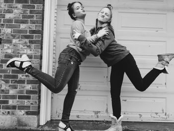 Full length of friends standing against wall