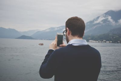 Rear view of man photographing at camera