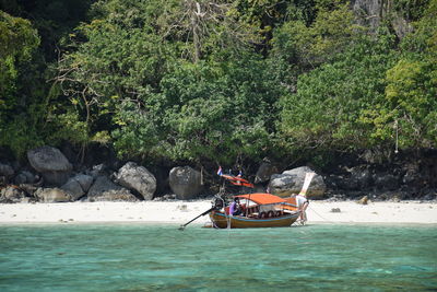 People in boat on river against trees