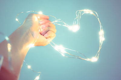 Digital composite image of hand holding heart shape against blue sky