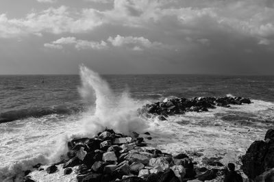 Waves splashing on sea against sky