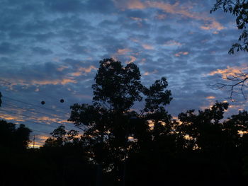 Low angle view of trees against cloudy sky