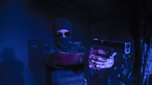 Teenage boy aiming gun while standing indoors