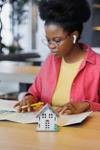 Side view of woman playing with model house on table