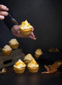 Person holding ice cream cone against black background