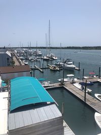 Boats moored at harbor against clear blue sky