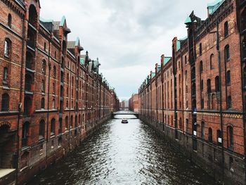 Canal amidst buildings in city against sky