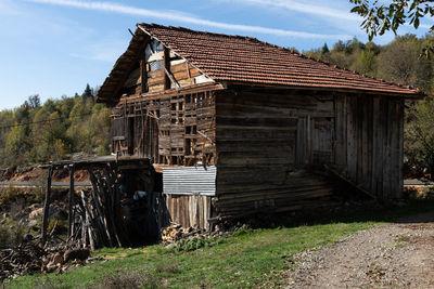 Old wooden house on field against sky