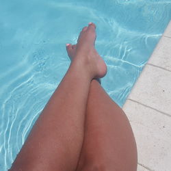 Low section of woman relaxing in swimming pool