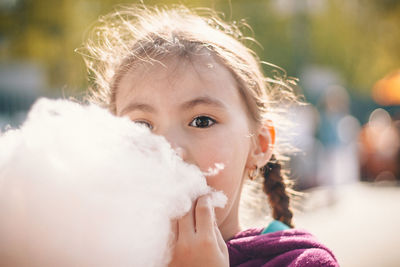 Close-up portrait of girl eating cotton candy