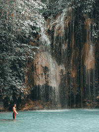 Full length of woman standing on rock in water