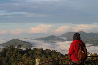 Side view of woman standing on observation point against sky