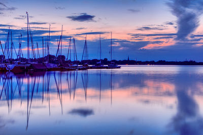 Sailboats moored in lake at sunset
