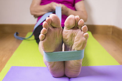 Low section of woman relaxing on exercising mat