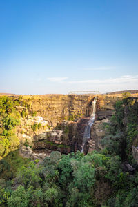 Waterfall falling from mountain top at forests at day from flat angle