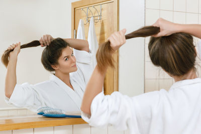 Woman tying hair in bathroom