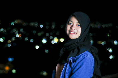 Portrait of smiling young woman at night