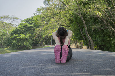Full length of young woman exercising on road at park