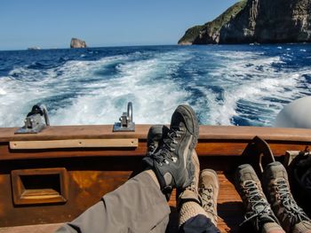 Low section of men relaxing in rowboat on sea