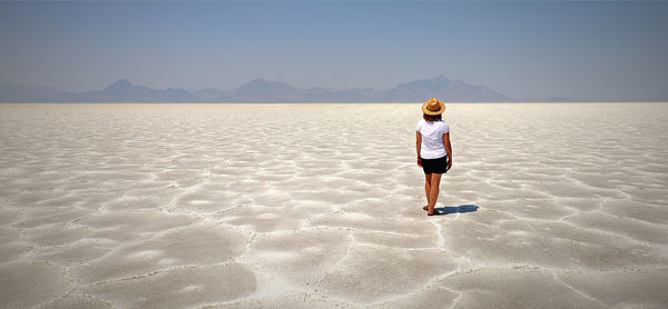 Rear view of woman standing at beach