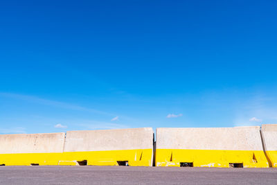 Low angle view of yellow flags against clear blue sky