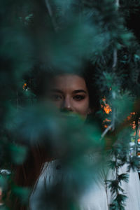 Portrait of young woman seen through plants 