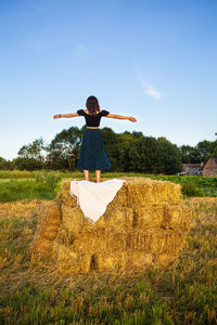 Rear view of woman standing on field against clear sky