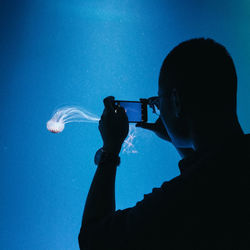 Man photographing jellyfish from mobile phone at aquarium