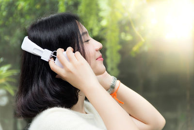 Side view of woman listening music on headphones