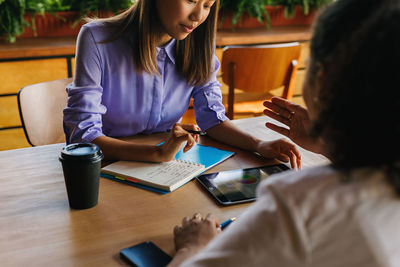 Midsection of woman holding smart phone on table