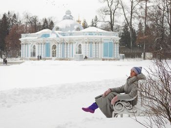 Rear view of woman sitting on snow covered field