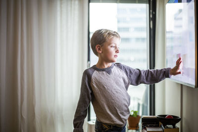 Boy touching screen of smart tv at modern home