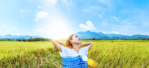 Rear view of woman standing on field against sky