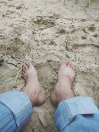 Low section of man standing on sand at beach