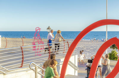 People standing at beach against clear sky