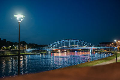 Illuminated bridge over river at night