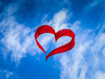 Low angle view of red flag against blue sky